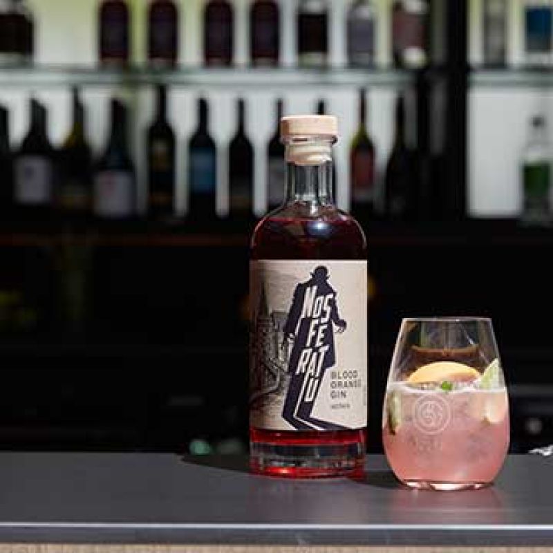 A bottle of Nosferatu Gin next to a cocktail